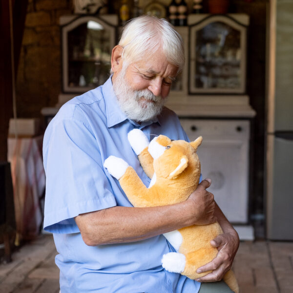 Ein älterer Herr spielt mit der RobiCare Smart Cat.